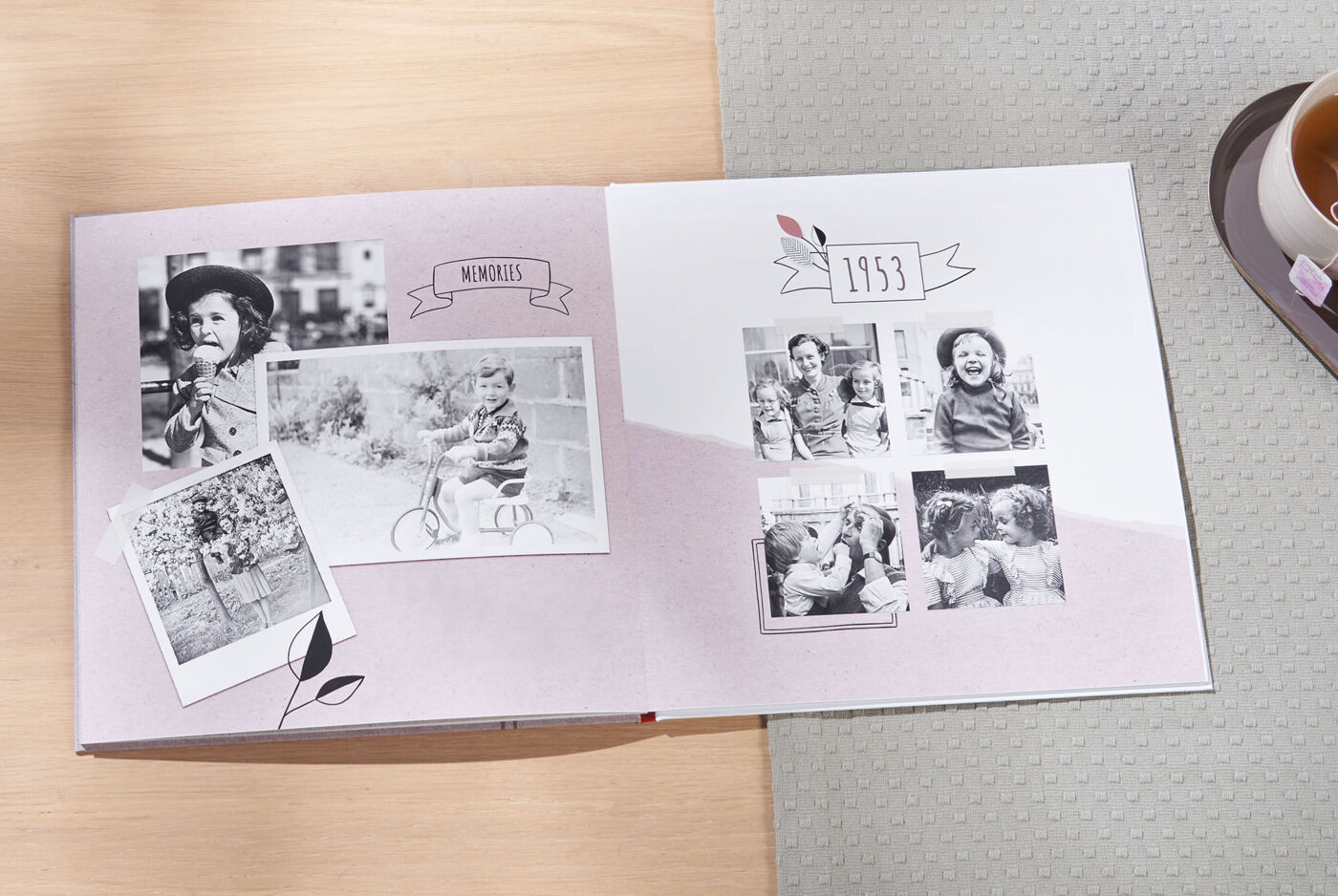 En åpen CEWE FOTOBOOK viser nostalgiske svart-hvitt bilder fra familieturer.