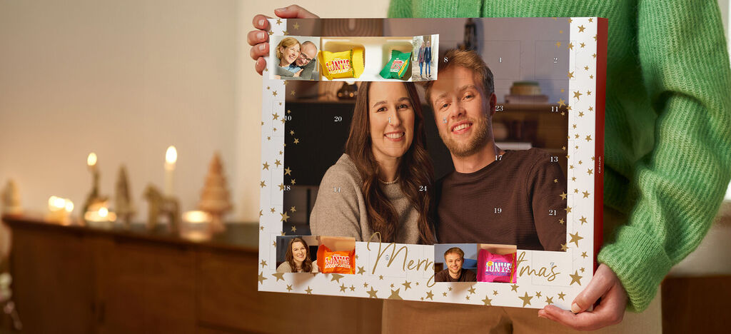 En adventskalender med bilder og godsaker, holdt av en person.